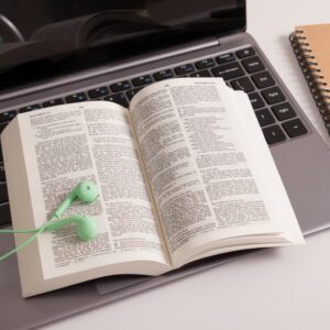 Headphones on open bible and laptop - online bible study concept